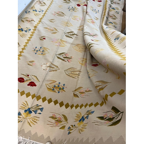 219 - A large embroidery rug with cream grounds and floral stemmed flowers 380cm x 285cm