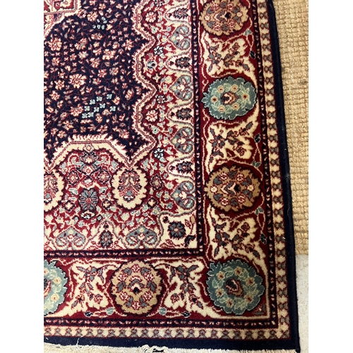 220 - A red ground Wilton rug with dark blue central panel with medallion 200cm x 134cm