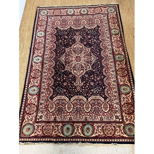 220 - A red ground Wilton rug with dark blue central panel with medallion 200cm x 134cm