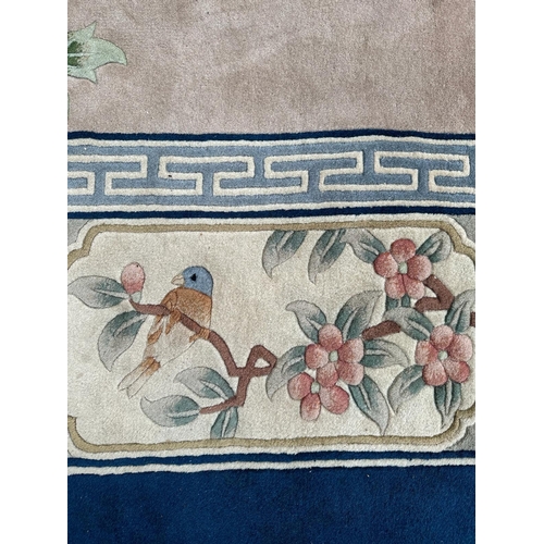 221 - A large Chinese style wool rug/carpet with pink grounds and geometric boarder  390cm x 270cm