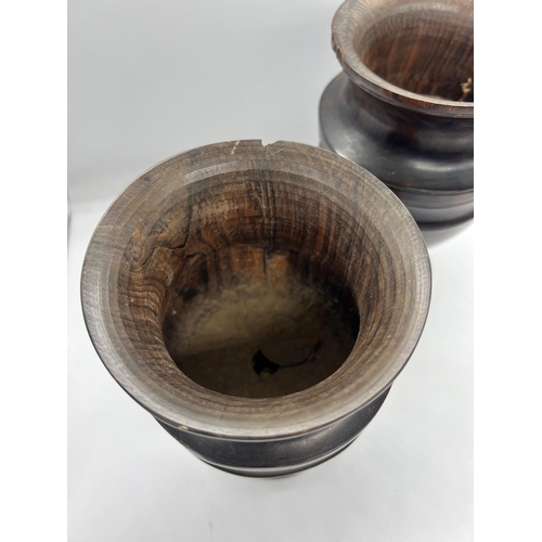 307 - A pair of turned treen trophy shape goblet vases on stem and circular foot (H24cm)