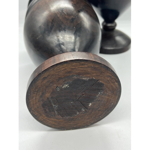 307 - A pair of turned treen trophy shape goblet vases on stem and circular foot (H24cm)