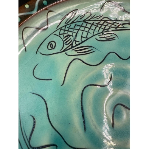 316 - A Studio pottery plate, blue grounds with painted fish detail signed to back