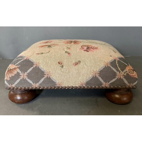 32 - A floral upholstered and studded footstool on bun feet