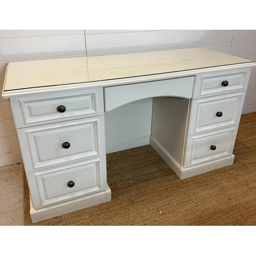 40 - A white painted knee hole dressing table with a glass top, long central drawer flanked by three shor... 