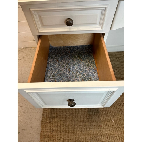 40 - A white painted knee hole dressing table with a glass top, long central drawer flanked by three shor... 