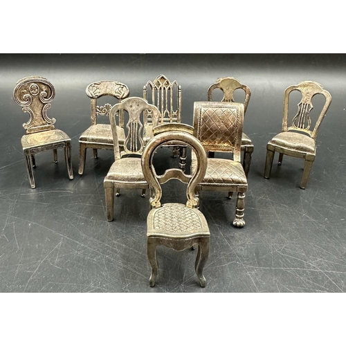 432 - A selection of eight white metal miniature chairs, various styles.