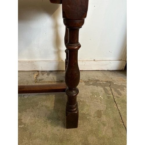 49 - An oak carved side table on turned legs with cross stretchers (H77cm W102cm D59cm)