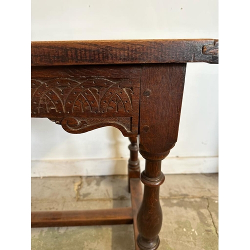 49 - An oak carved side table on turned legs with cross stretchers (H77cm W102cm D59cm)