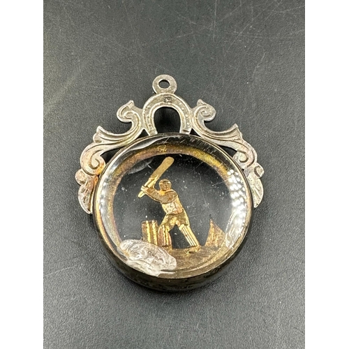 492 - A silver and glass fob featuring a cricketer in action