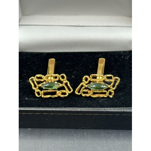 509 - A pair of 18ct gold cuff links with central green stones, hallmarked for London, bearing the makers ... 