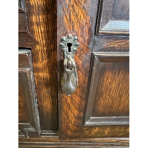 58 - An oak dresser base with two central drawers flanked by two cupboards with carved fronts and relief ... 