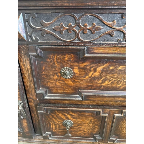 58 - An oak dresser base with two central drawers flanked by two cupboards with carved fronts and relief ... 