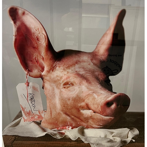 658 - A signed framed print of Gordon The Pig, The pigs head sit on a butchers block with a swing tag 