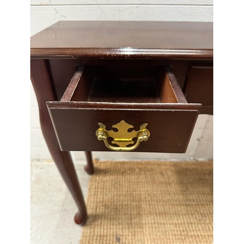 115 - A three drawer magnolia console table with brass drop down handles (H69cm W92cm D31cm)