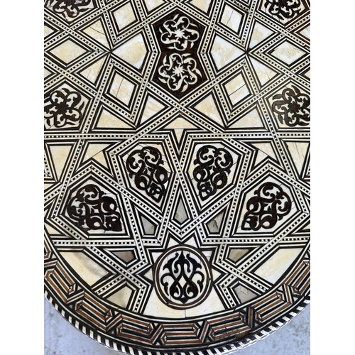 121 - A Moroccan style low pedestal table on splayed legs with geometrical mother of pearl and ebony inlay... 