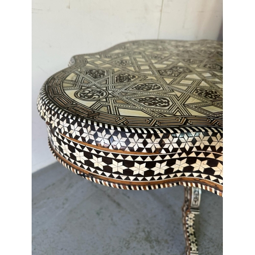 121 - A Moroccan style low pedestal table on splayed legs with geometrical mother of pearl and ebony inlay... 