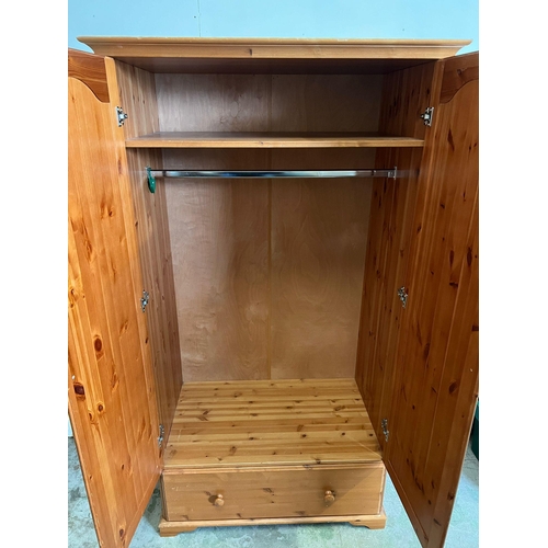 212 - A pine double wardrobe with drawer under (H187cm W103cm D59cm)