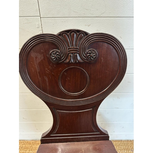 214 - A mahogany carved hall chair c 1820, the shaped back carved with reeded scrolls. AF