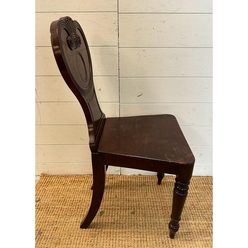 214 - A mahogany carved hall chair c 1820, the shaped back carved with reeded scrolls. AF