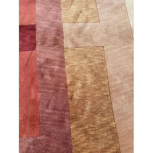 252 - A beige ground wool rug in red, brown and orange 300cm x 210cm