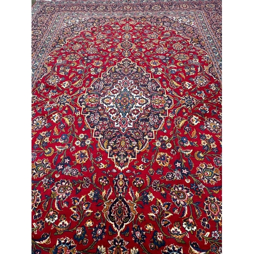 255 - A hand knotted wool Kashan rug, rich red background with central medallion and elaborate decoration ... 