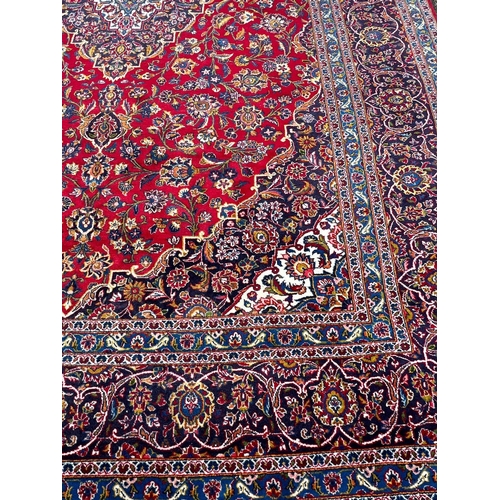 255 - A hand knotted wool Kashan rug, rich red background with central medallion and elaborate decoration ... 