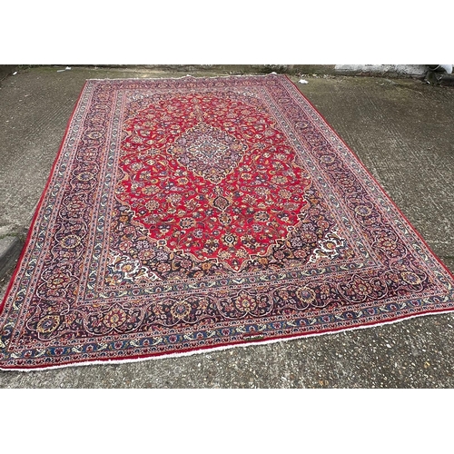 255 - A hand knotted wool Kashan rug, rich red background with central medallion and elaborate decoration ... 