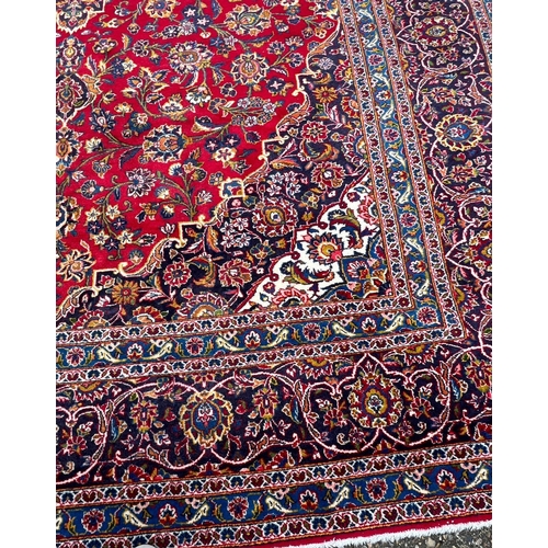 255 - A hand knotted wool Kashan rug, rich red background with central medallion and elaborate decoration ... 