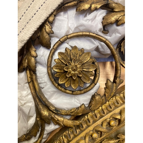 256 - A large George lll gilt wood oval mirror. The frame with urn cresting and floral and foliate scrolls... 