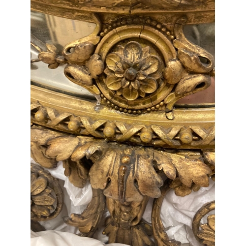 256 - A large George lll gilt wood oval mirror. The frame with urn cresting and floral and foliate scrolls... 