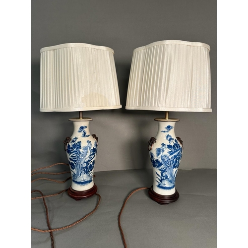 427 - A pair of Chinese blue and white table lamps in a floral bird pattern with foo dogs to side