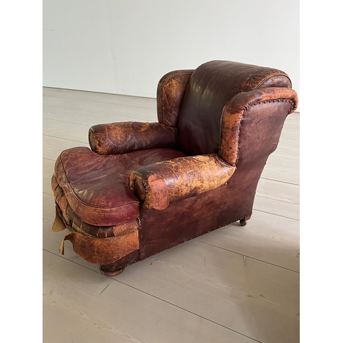 50 - An antique leather club chair in a distressed manner (H84cm W97cm SH37cm)