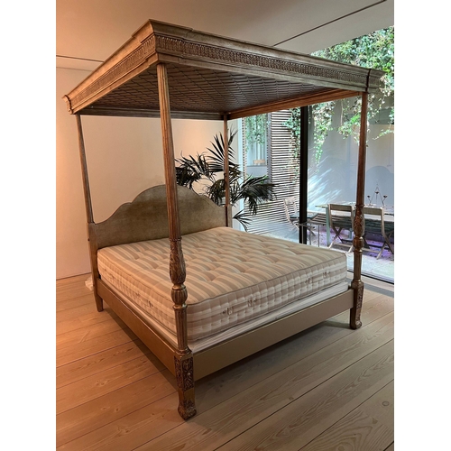 65 - A four poster bed with carved posts and scrolling finals, the shaped bed head and canopy above carve... 