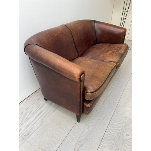 68 - A two seater leather sofa, with tapering legs and a dark tan piping to edge (H77cm W144cm D70cm SH48... 