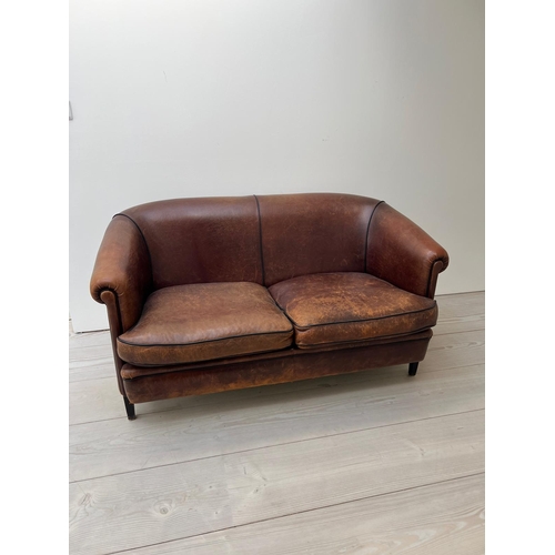 68 - A two seater leather sofa, with tapering legs and a dark tan piping to edge (H77cm W144cm D70cm SH48... 