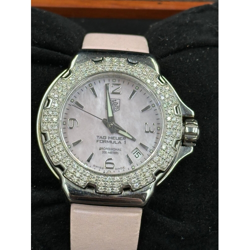 704 - A Ladies Tag Heuer Formula 1 watch with diamond bezel, box and papers on pink leather strap with pin... 