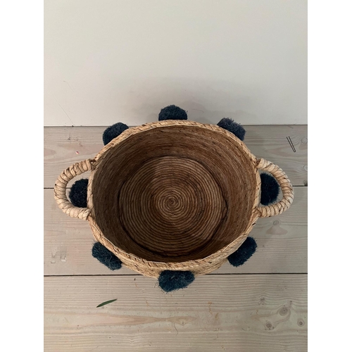 790 - A wove rush basket with pom poms (H32cm W59cm)