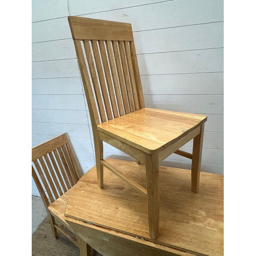 157 - A light oak or pine drop sided table with two slat back chairs