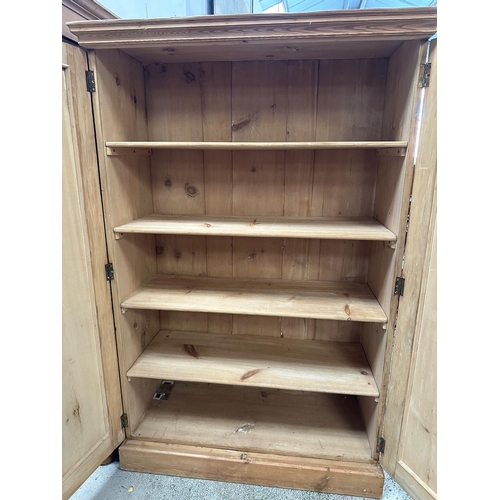 36 - A distressed pine two door cupboard opening to four shelves (H168cm W109cm D46cm)