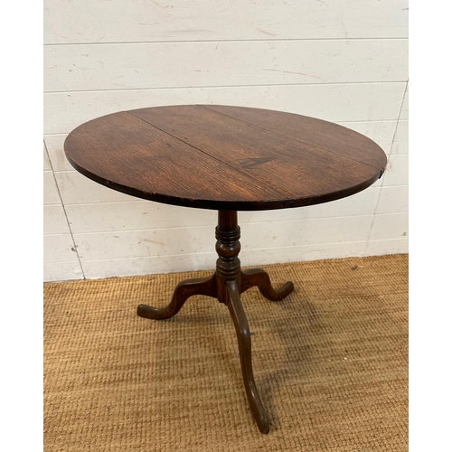 47 - A circular oak tilt top table on turned central support and splayed tripod legs (H66cm Dia71cm