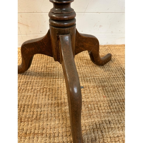 47 - A circular oak tilt top table on turned central support and splayed tripod legs (H66cm Dia71cm