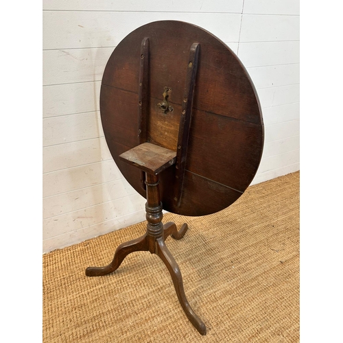 47 - A circular oak tilt top table on turned central support and splayed tripod legs (H66cm Dia71cm