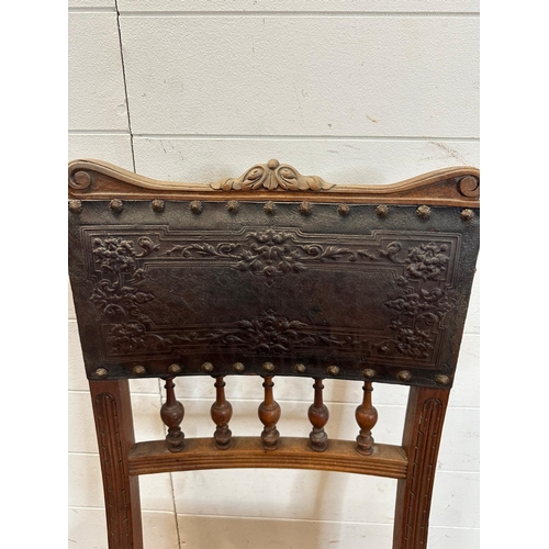 49 - A French oak and embossed leather hall chair, turned front legs and ornate floral pattern to seat ba... 