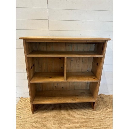 58 - A pine three shelf bookcase, the middle shelf separated into two compartments (H102cm W96cm D31cm)