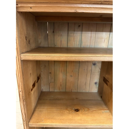 58 - A pine three shelf bookcase, the middle shelf separated into two compartments (H102cm W96cm D31cm)