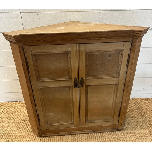 60 - A pine two door corner cabinet with brass drop handles opening to two shelves (H67cm W68cm D38cm)