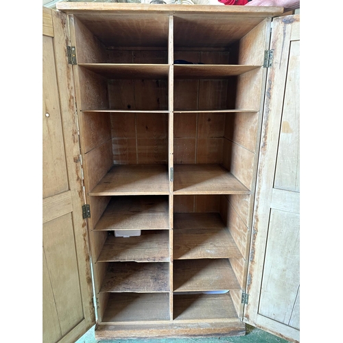 63 - A vintage weathered pine two door cupboard opening to eleven shelved compartments (H125cm W66cm D49c... 