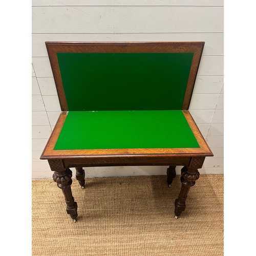 77 - A Victorian card table, fold over top opening to reveal green baize interior on reeded legs and cast... 