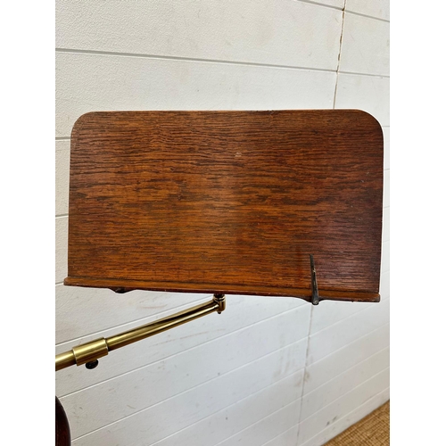 171 - A vintage music stand with brass central column and adjustable arm on cast iron lions paw feet